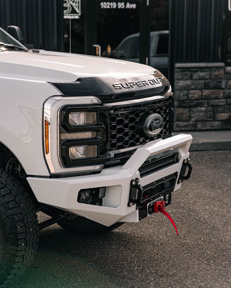 Front corner of a Ford Super Duty fitted with a white Gridiron bumper at 10219 95 Ave
